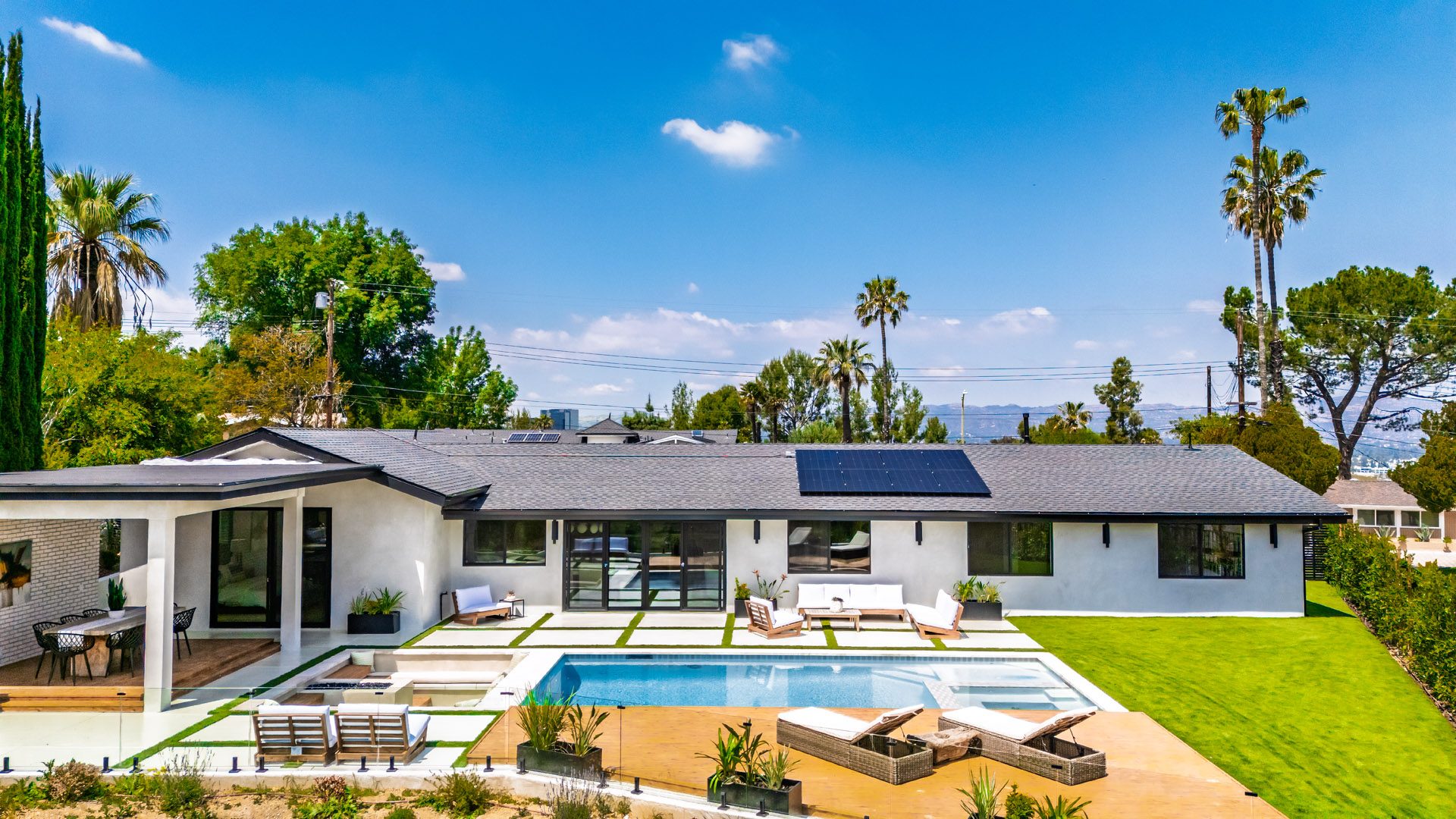 Califa St residence with pool, lawn and covered terrace under a clear Los Angeles sky