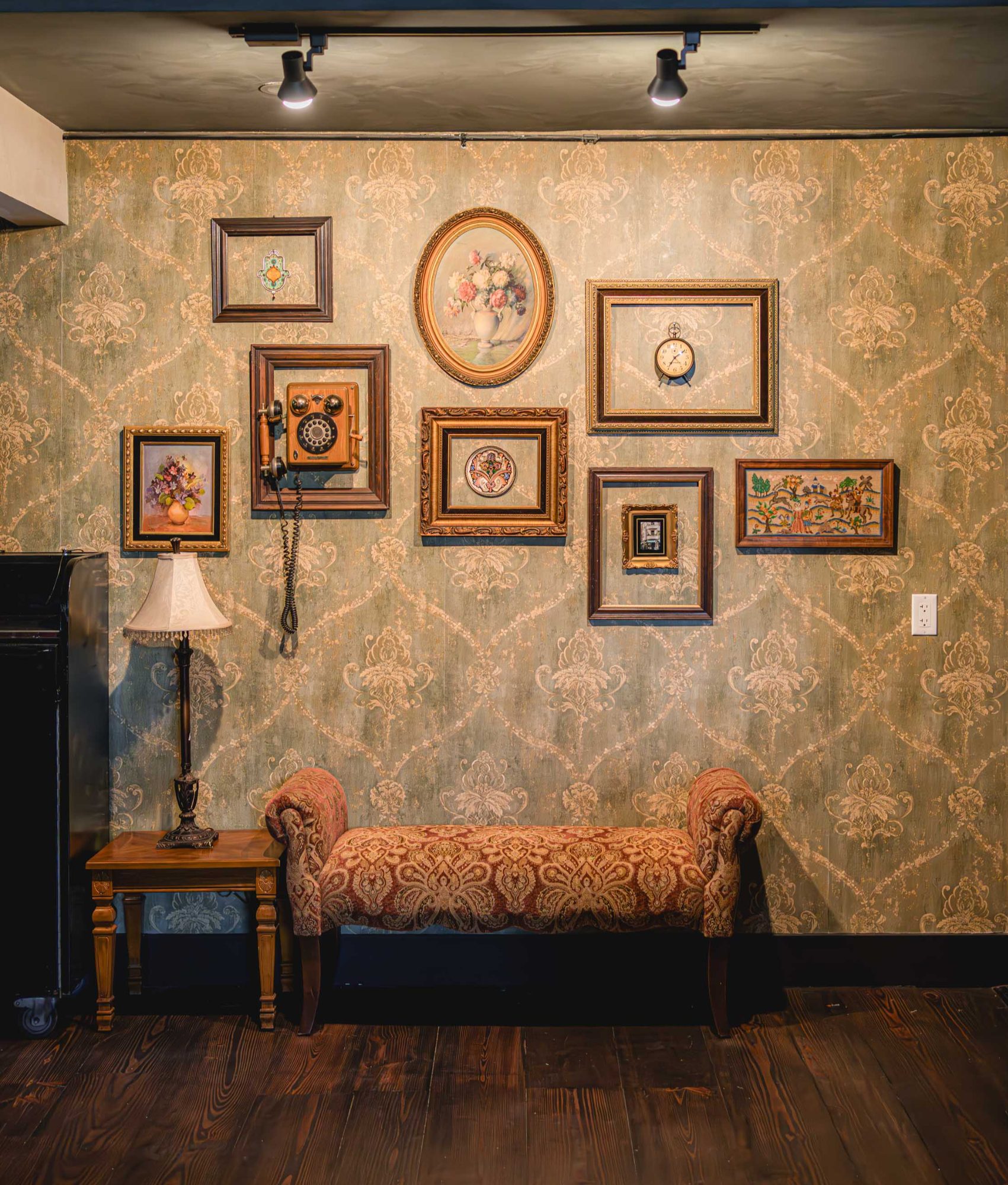 Interior detail of patterned wallpaper, framed artwork and a vintage bench