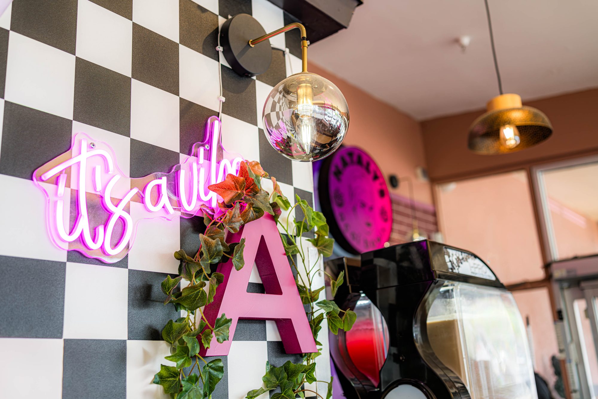Checkerboard wall and pink neon signage at the Nataly's Acai entrance